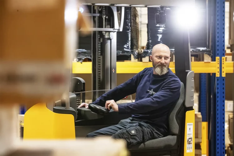 Ein Lagermitarbeiter ist mit dem Gabelstapel in der neuen Lagerhalle unterwegs.