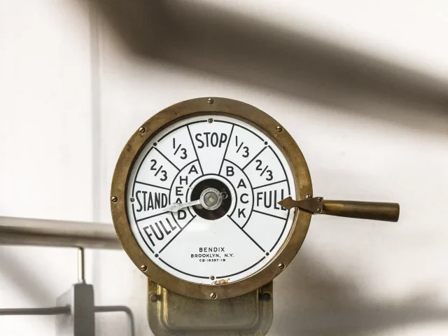 Historischer Maschinentelegraf auf einem Schiff, runde Messinganzeige mit Skala ‚Stop/Stand/Full‘ (Ahead/Back); Hebel steht auf ‚Full‘.